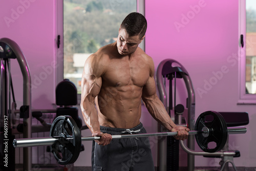 Man In The Gym Exercising Biceps With Barbell