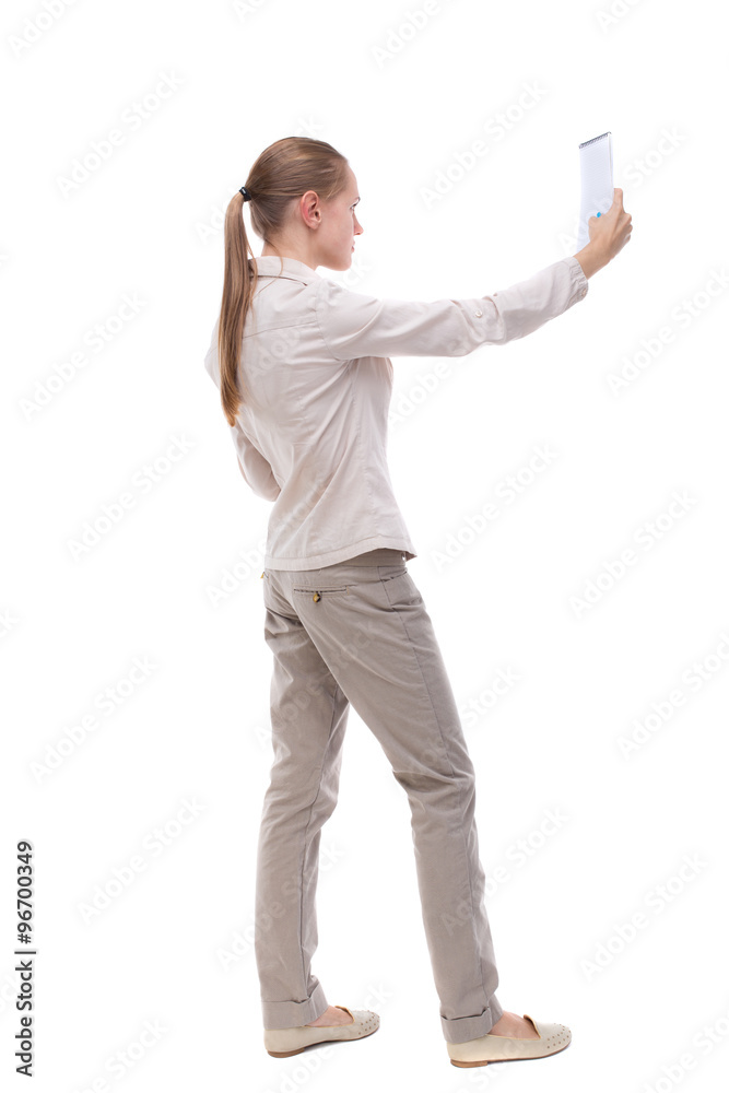 back view of  stands woman takes notes in a notebook. girl  watc