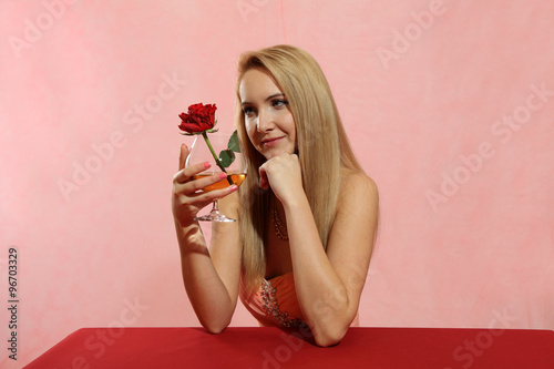 Piękna dziewczyna blondynka z kielichem i różą.