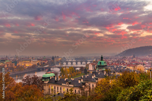 General view of bridges in Prague in autumn. Yellow trees flavor the cityscape. Fog over the city.