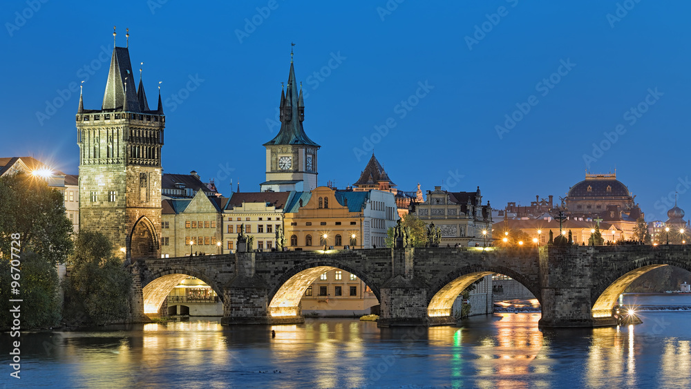 Evening view of the Charles Bridge in Prague, Czech Republic, with Old Town Bridge Tower, Old Town Water Tower and dome of the National Theatre