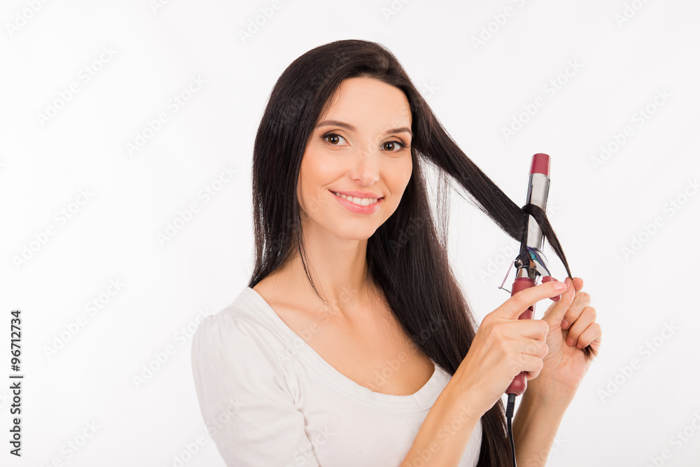 Obraz premium Pretty young woman curling her long hair