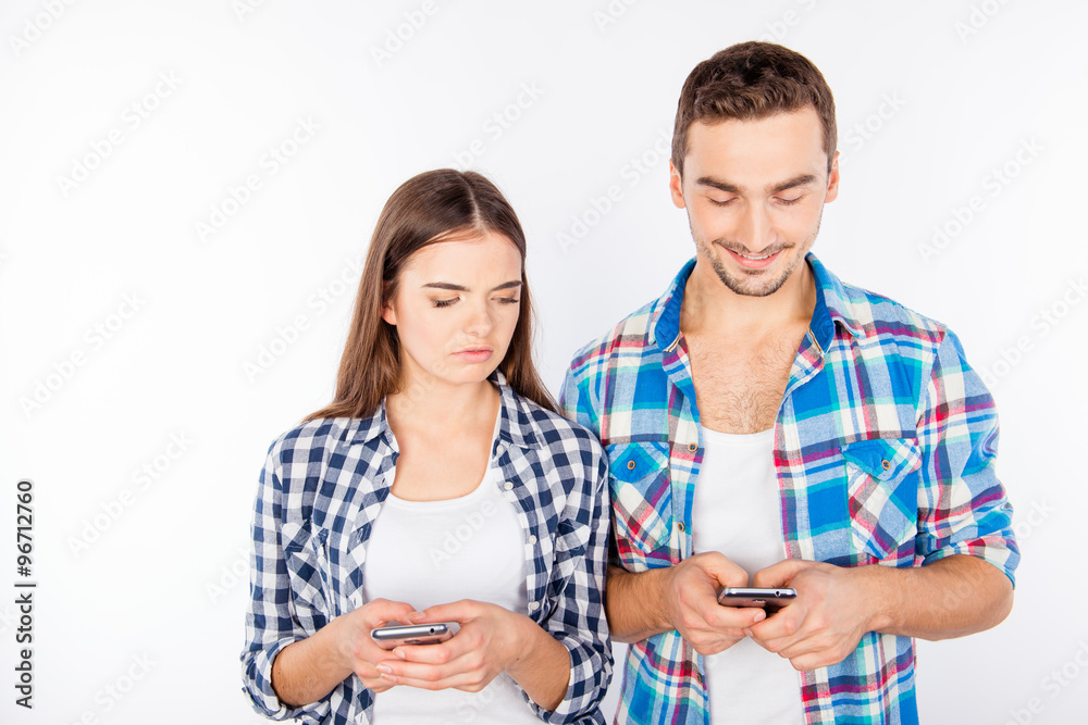 Cheerful man typing message ignoring his girlfriend Cheerful man typing message ignoring his girlfriend