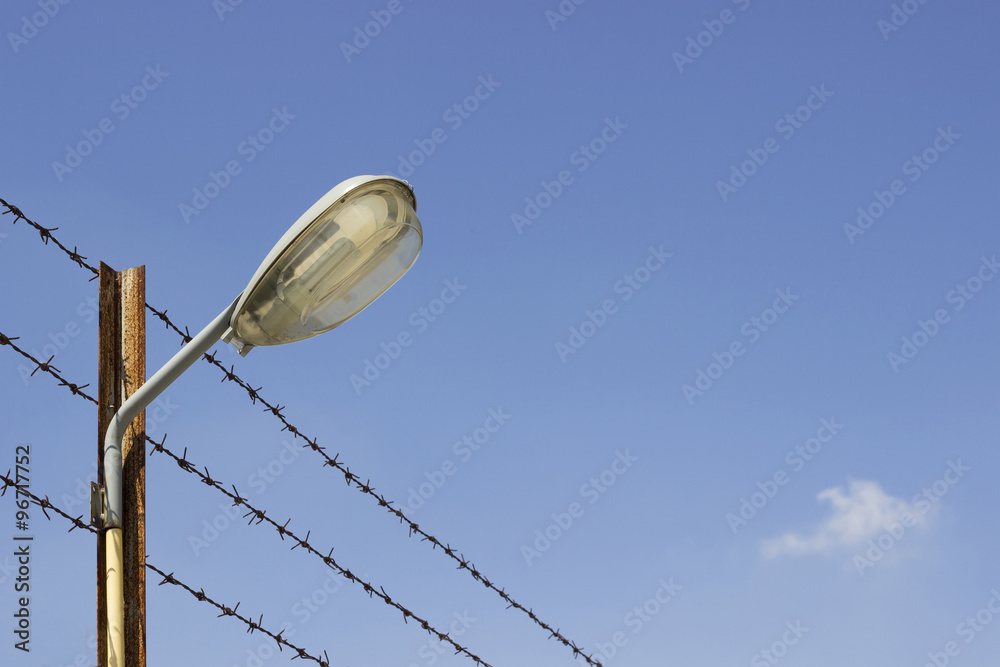 Obraz premium Recessed lighting in the area and a barbed wire barricade in restricted areas a backdrop of blue sky.