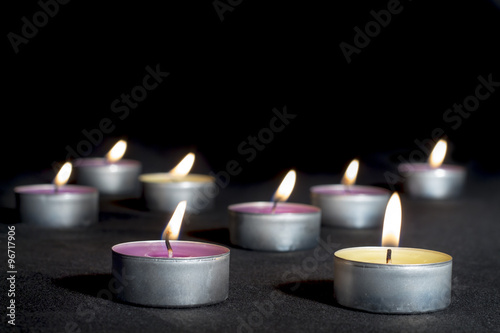 Scented candles of different fragrances, with metal base, on black background