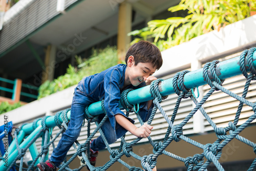 Little boy climbing on the rope at playground