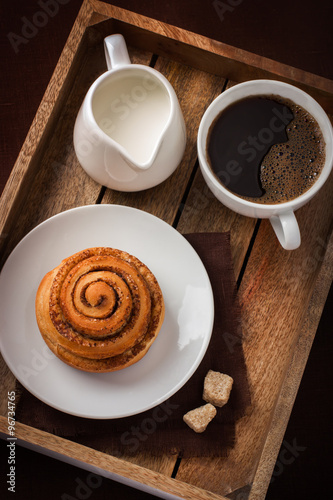 Fototapeta cinnamon roll,  cup of coffee and cream  on wooden tray