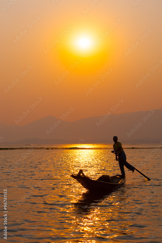 INLE LAKE VILLAGE MYANMAR : Silhouette People rows the wooden boat by his leg in Inle Lake