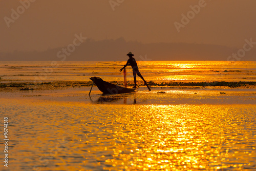 INLE LAKE VILLAGE MYANMAR : Silhouette People rows the wooden boat by his leg in Inle Lake © Songkhla Studio