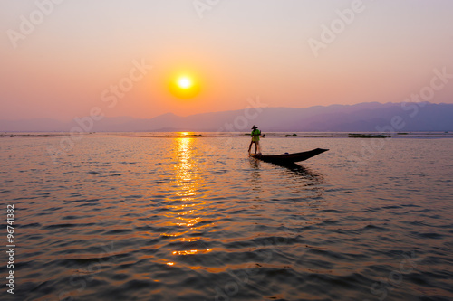 INLE LAKE VILLAGE MYANMAR : Silhouette People rows the wooden boat by his leg in Inle Lake © Songkhla Studio