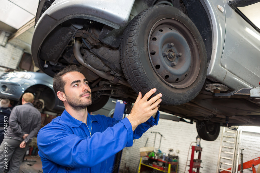 Young attractive mechanic working on a car at the garage Young attractive mechanic working on a car at the garage
