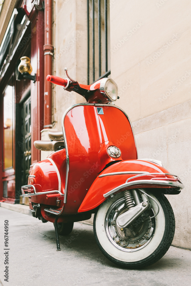 Naklejka premium Czerwony skuter retro na europejskiej ulicy