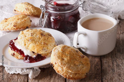 Scones with jam and tea with milk on the table. horizontal
