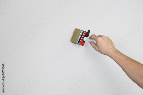 Ein Frauenarm mit einem Pinsel in der Hand streicht eine Wand an