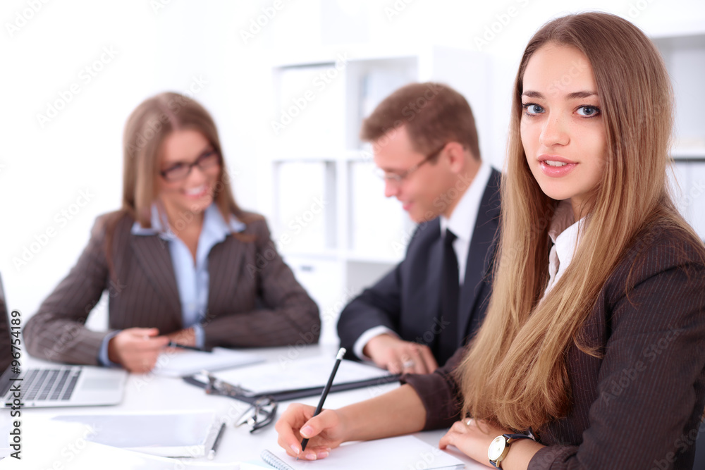 A group of business people at a meeting on the background of office. Focus on a beautiful brunette A group of business people at a meeting on the background of office. Focus on a beautiful brunette