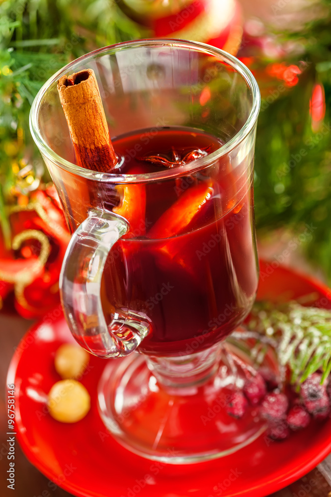 Glass of mulled wine by Christmas tree with decorations. Delicious drink for party. Glass of mulled wine by Christmas tree with decorations. Delicious drink for party.