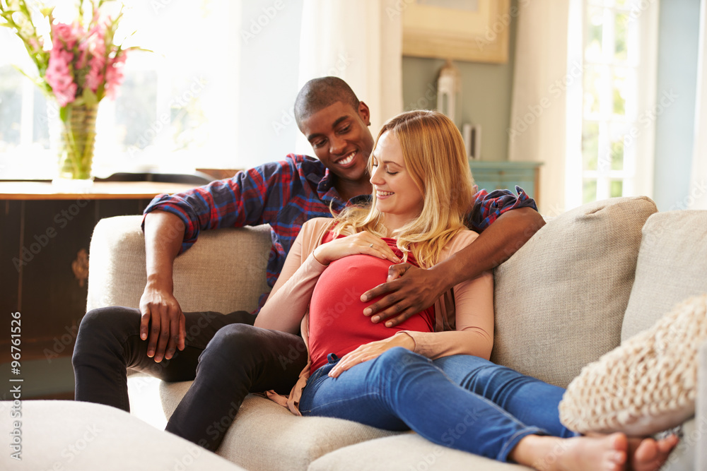 Pregnant Couple At Home Relaxing On Sofa Together Pregnant Couple At Home Relaxing On Sofa Together