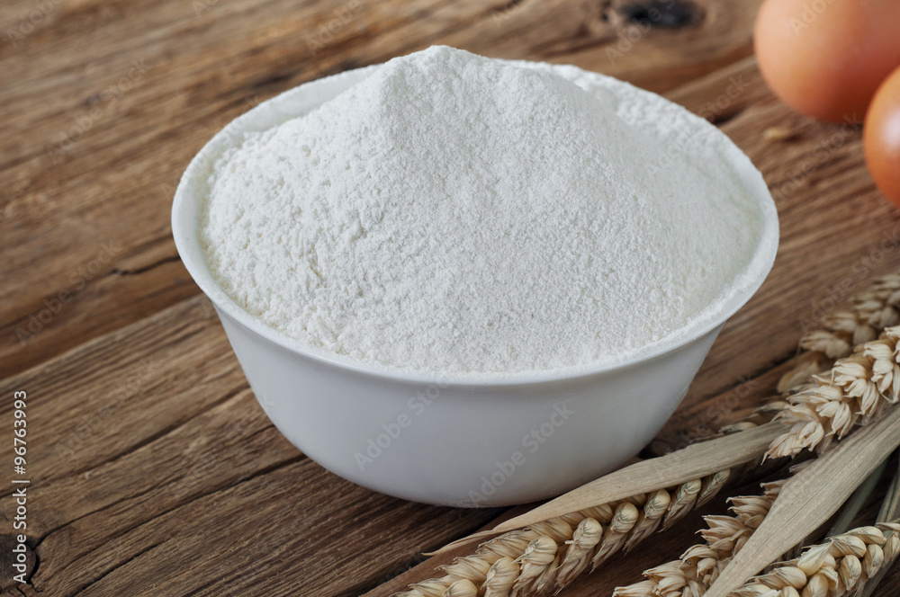 Flour in a bowl close up on wooden table Flour in a bowl close up on wooden table