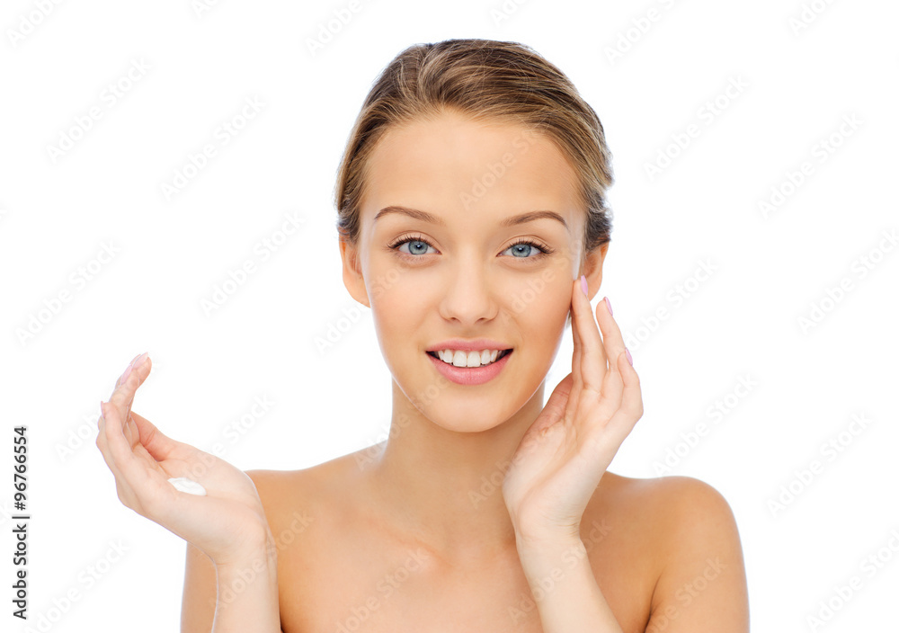happy young woman applying cream to her face happy young woman applying cream to her face