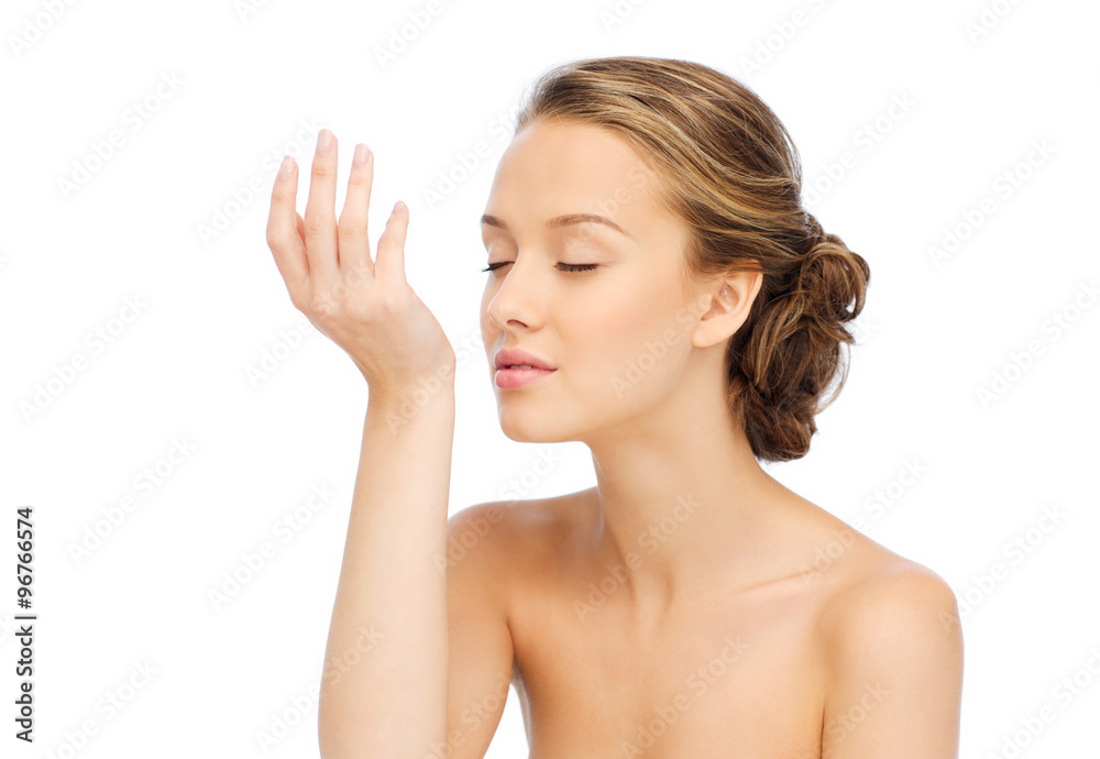 woman smelling perfume from wrist of her hand woman smelling perfume from wrist of her hand
