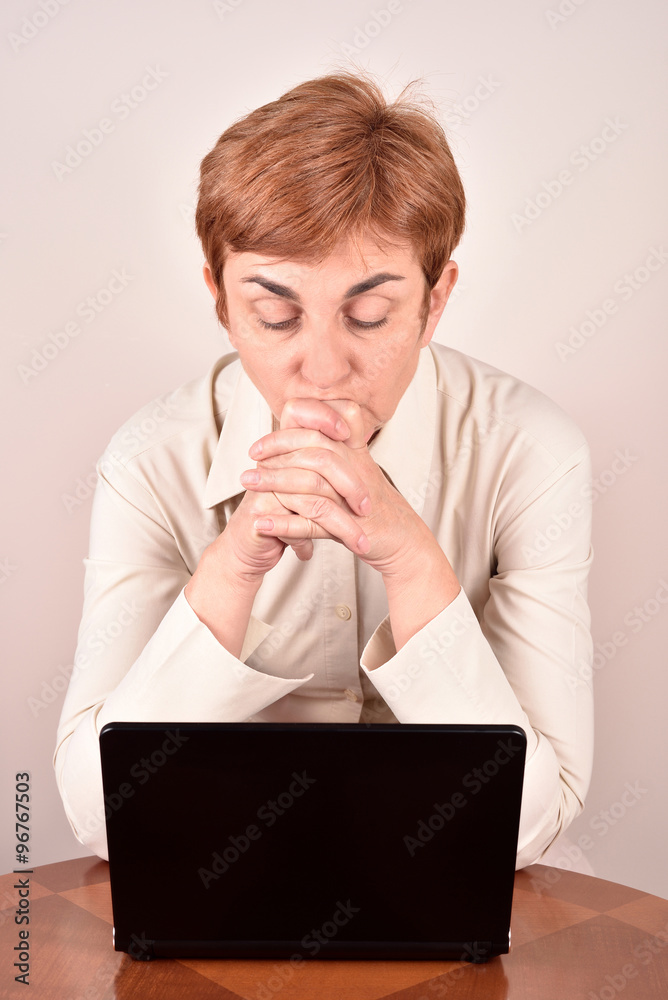 Worried businesswoman leaning her head on the hands and looking at the laptop Worried businesswoman leaning her head on the hands and looking at the laptop