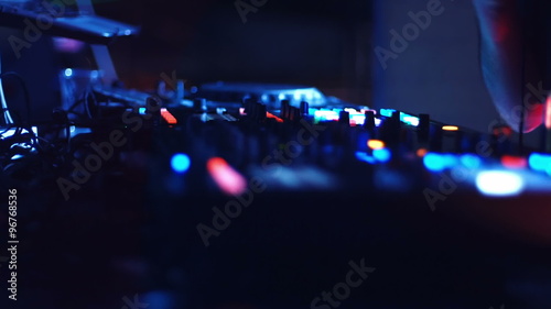 DJ mixing tracks on console at dance music party