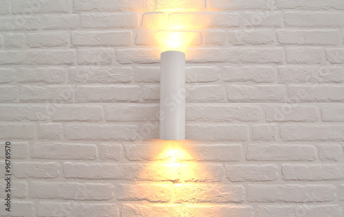 The wall lamp with illumination on a white brick wall