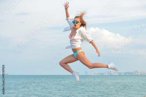 Portrait of beautiful young woman having fun in high jump over copy space background outdoors
