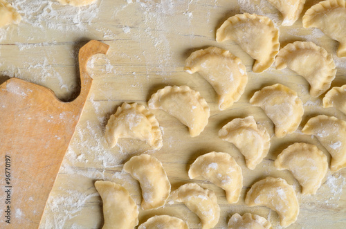 Sculpt pierogy and pelmeni concept. Include rustic cutting board, making pierogies on a rustic wooden table. Dumpling recipe.