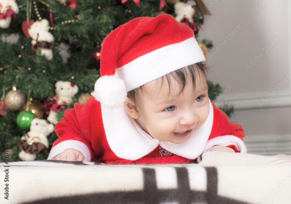 Small child in the clothes of Santa Claus. The girl is lying on her stomach. Small child in the clothes of Santa Claus. The girl is lying on her stomach.