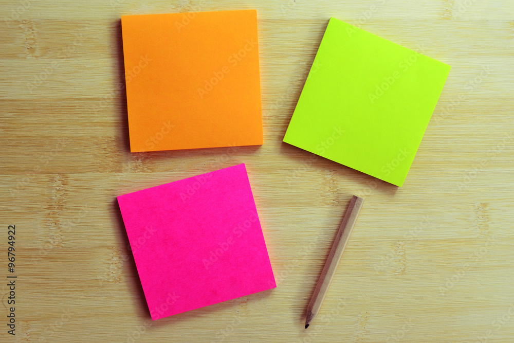 Colorful post it note and wooden  pencil on wooden board