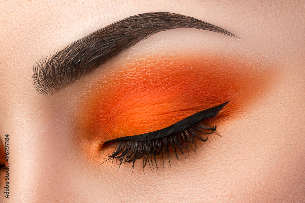 Close-up of woman eye with beautiful orange smokey eyes with bla - obrazy, fototapety, plakaty 