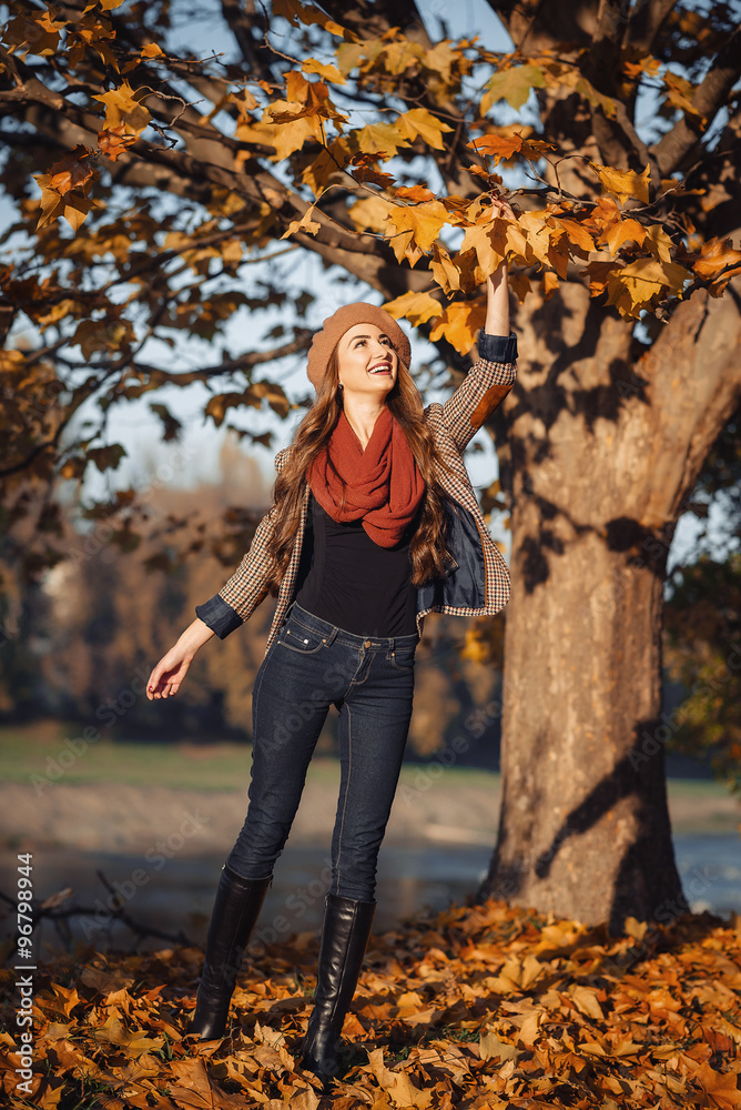 slender young brunette beautiful girl with long hair in a beret with a scarf and coat walks in autumn park with a lot of yellow and orange leaves slender young brunette beautiful girl with long hair in a beret with a scarf and coat walks in autumn park with a lot of yellow and orange leaves