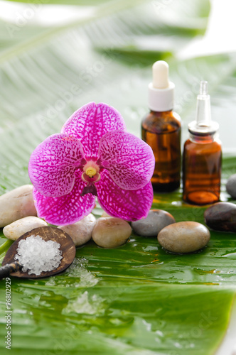 spa setting with pebbles ,stones,oil , orchid and banana leaf
