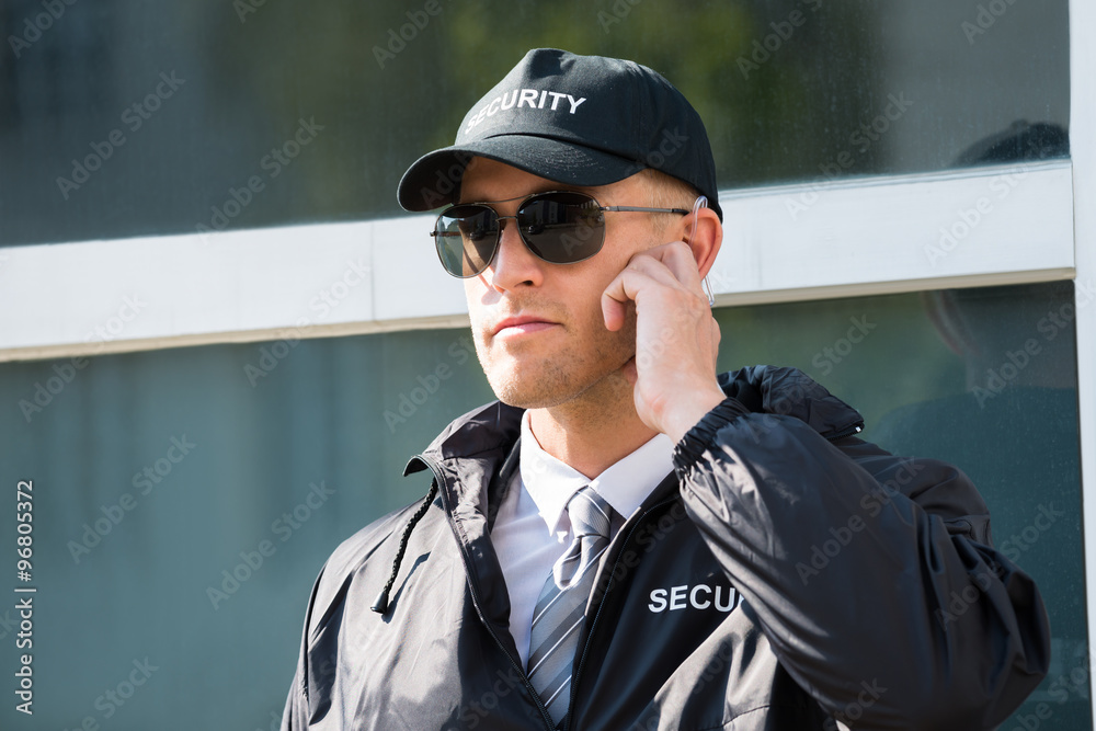 Young Security Guard Standing In Front Of The Entrance Young Security Guard Standing In Front Of The Entrance