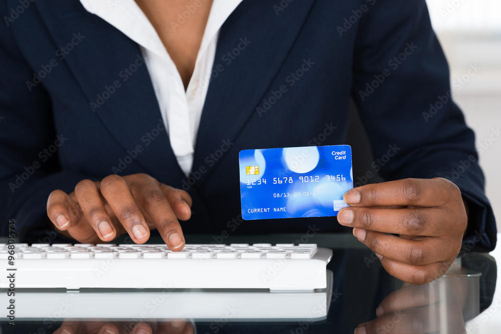 Fototapeta premium Person's Hand Holding Credit Card While Typing On Keyboard