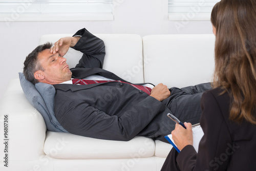 Patient Relaxing On Couch In Front Of A Psychiatrist