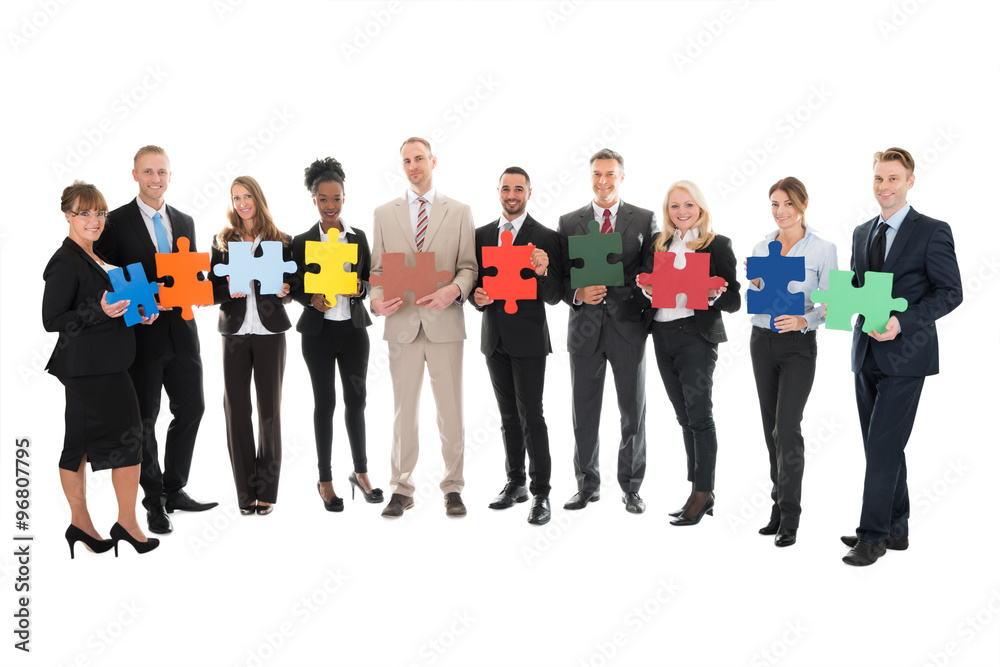 Portrait Of Happy Business Team Holding Jigsaw Pieces