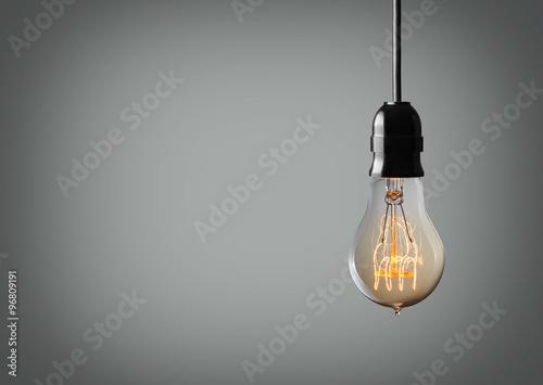 Vintage hanging light bulb over gray background photo