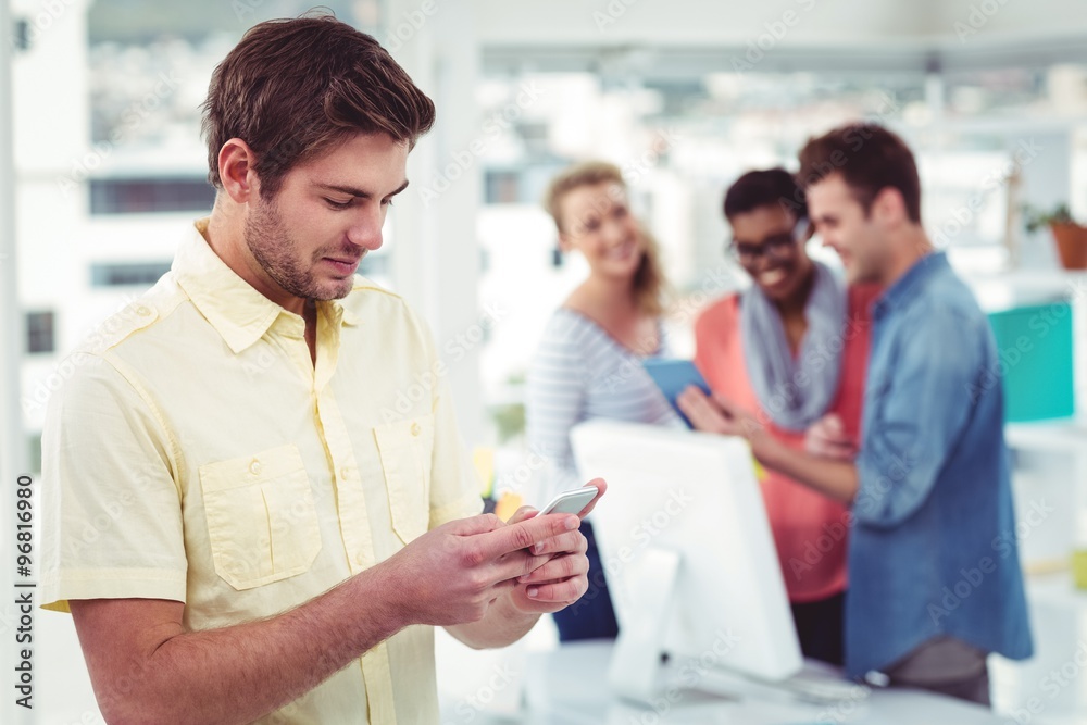 Creative businessman using smartphone in front of colleagues Creative businessman using smartphone in front of colleagues