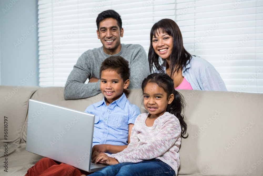 Smiling family using laptop on sofa Smiling family using laptop on sofa