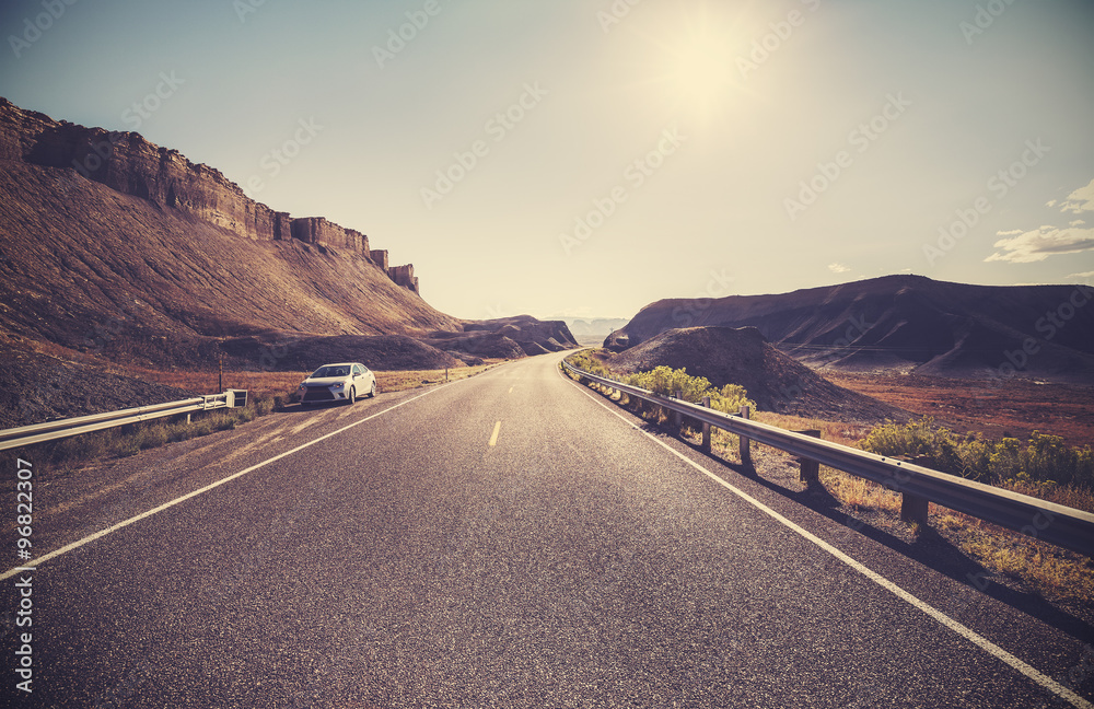 Retro toned desert highway against sun, travel concept