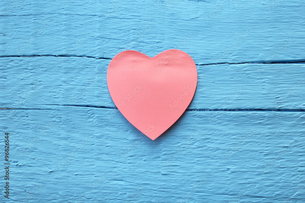 Fototapeta premium Blank pink paper note with heart shape on grunge blue wooden background with copy space