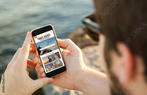 Man using his mobile phone on the coast to travel online photo