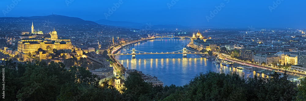 Fototapeta premium Evening panorama of Budapest, view from Gellert Hill, Hungary. The panorama shows: Buda with Buda Castle, Danube river with Szechenyi Chain Bridge, Pest with Hungarian Parliament Building.