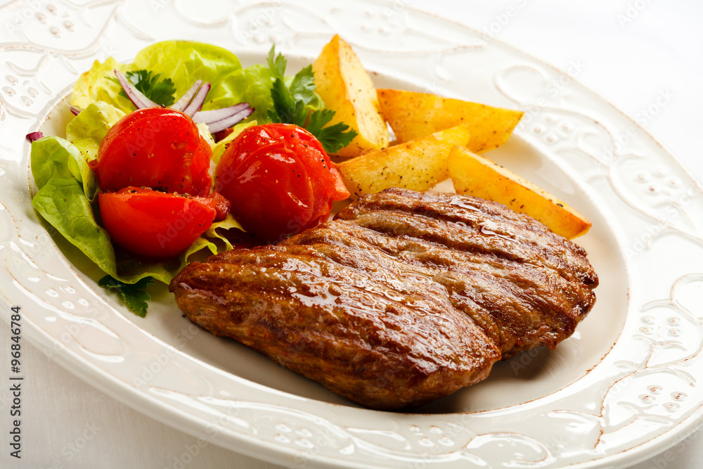 Grilled steak, baked potatoes and vegetable salad 