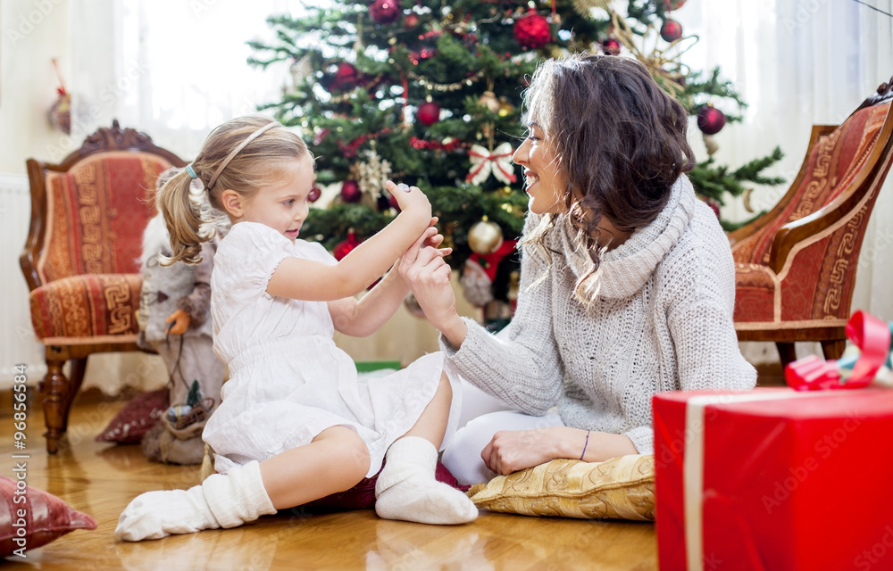 Mother and daughter in front of Christmas tree, opening presents Mother and daughter in front of Christmas tree, opening presents