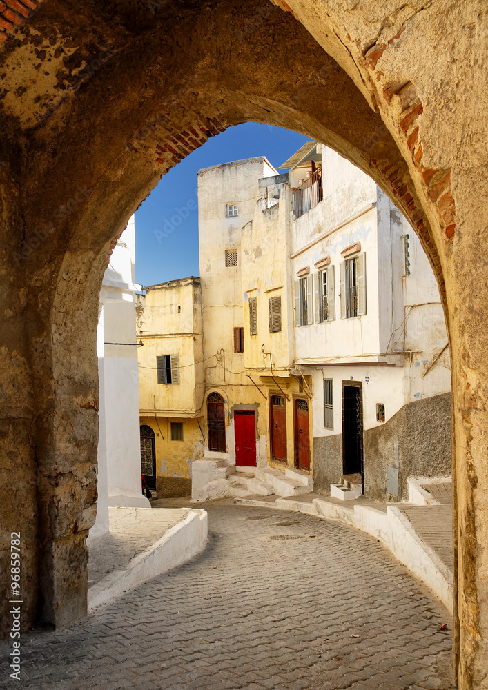 Naklejka premium Narrow street in Tangier, view through the town wall gate, Morocco