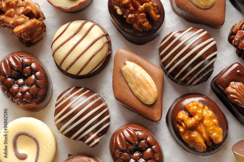 Assorted aligned bonbons on a white textured paper Top view photo