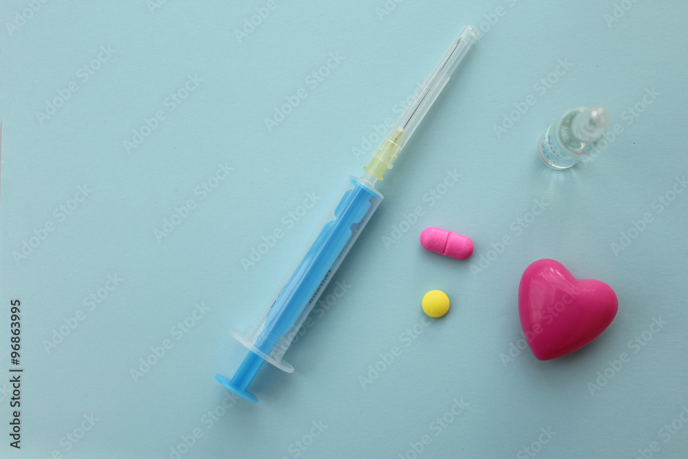 Syringe, needle, ampule and pills on blue background - medicine concept Syringe, needle, ampule and pills on blue background - medicine concept